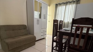 Un espace de vie compact comprenant un canapé, une table à manger avec des chaises, une armoire et un réfrigérateur.