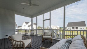 A covered porch with wicker furniture, large windows, and a view of houses. - 15325 West Kea Way, Tower Hill: 4  BR, 3.5  BA House in Lewes, Sleeps 8 (Lewes)