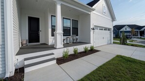 A two-story house with a covered front porch, a garage, and a well-maintained lawn. - 15325 West Kea Way, Tower Hill: 4  BR, 3.5  BA House in Lewes, Sleeps 8 (Lewes)