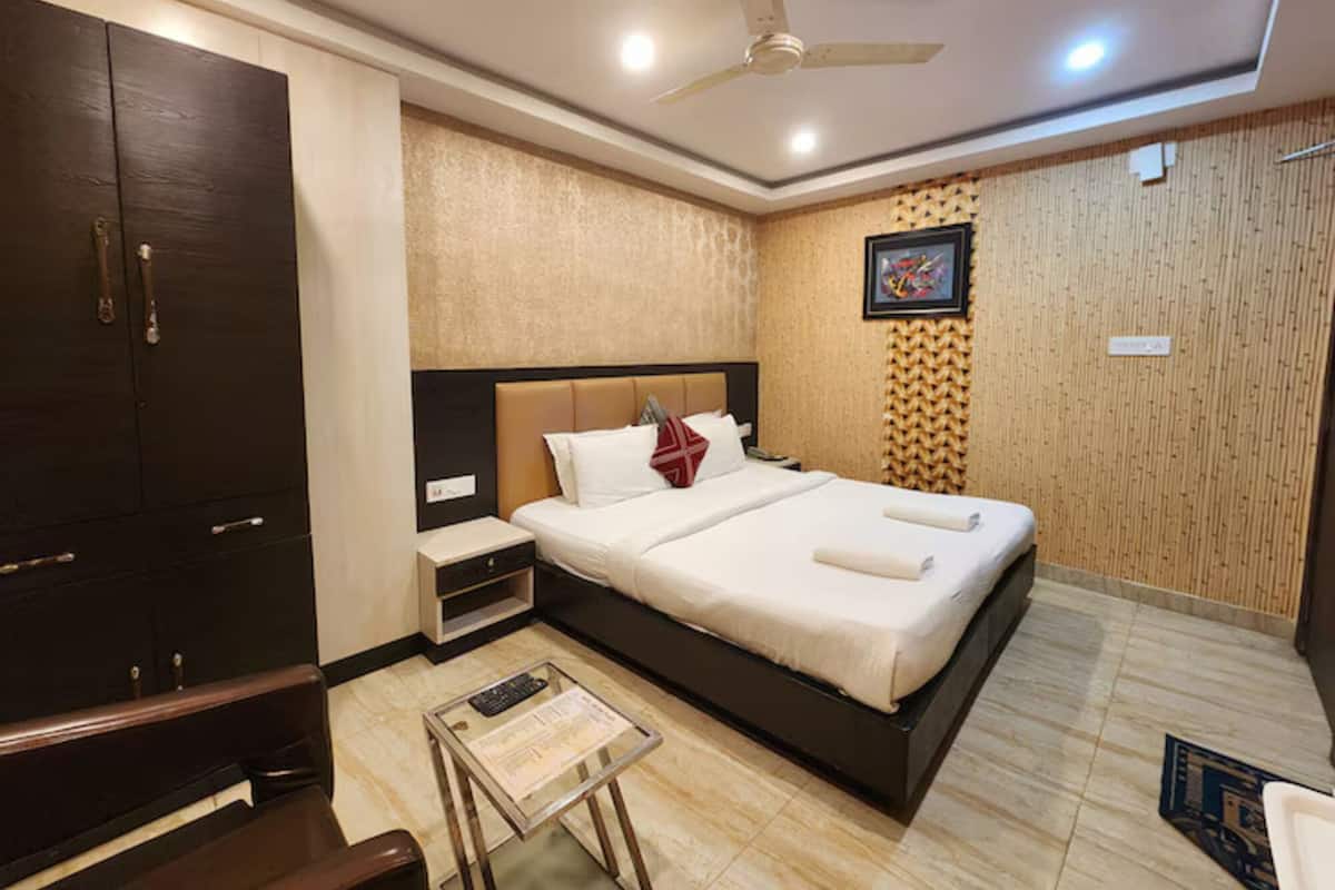 Ein Hotelzimmer mit Bett, Kleiderschrank, Deckenventilator und einem kleinen Tisch mit Fernbedienung.