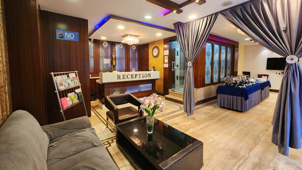 A reception area with a reception desk, a sofa, a coffee table with a vase, and a curtain. - Hotel Orchid Plaza (Kolkata)