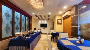 A conference room with long tables, a chandelier, and a television on the wall. - Hotel Orchid Plaza (Kolkata)