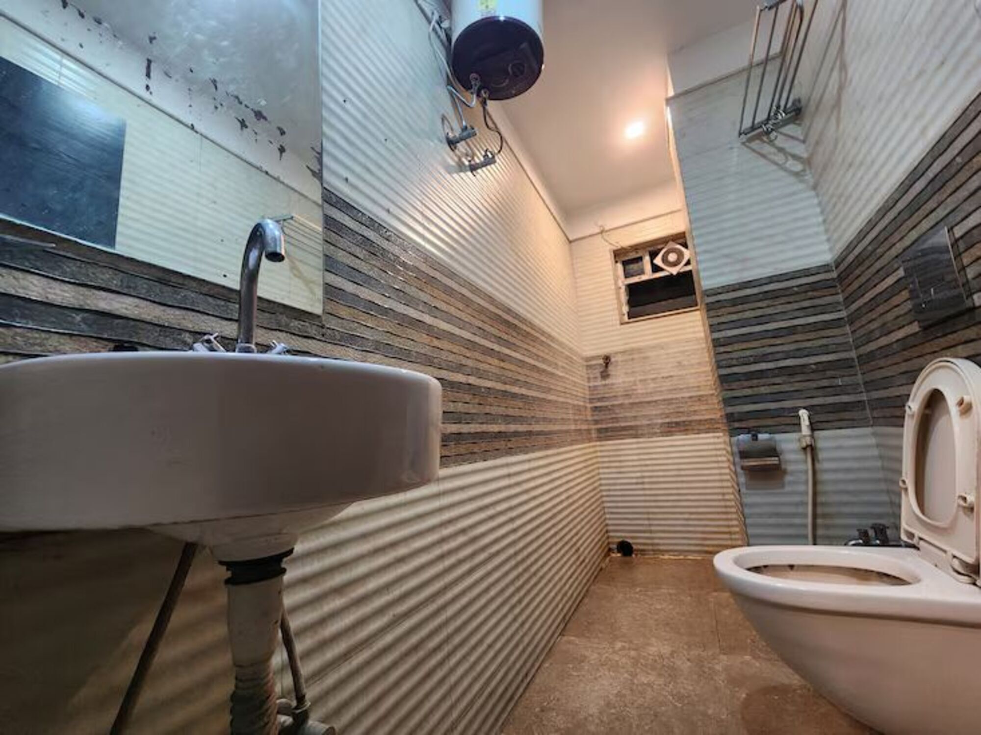 A narrow bathroom with a sink, toilet, and shower.