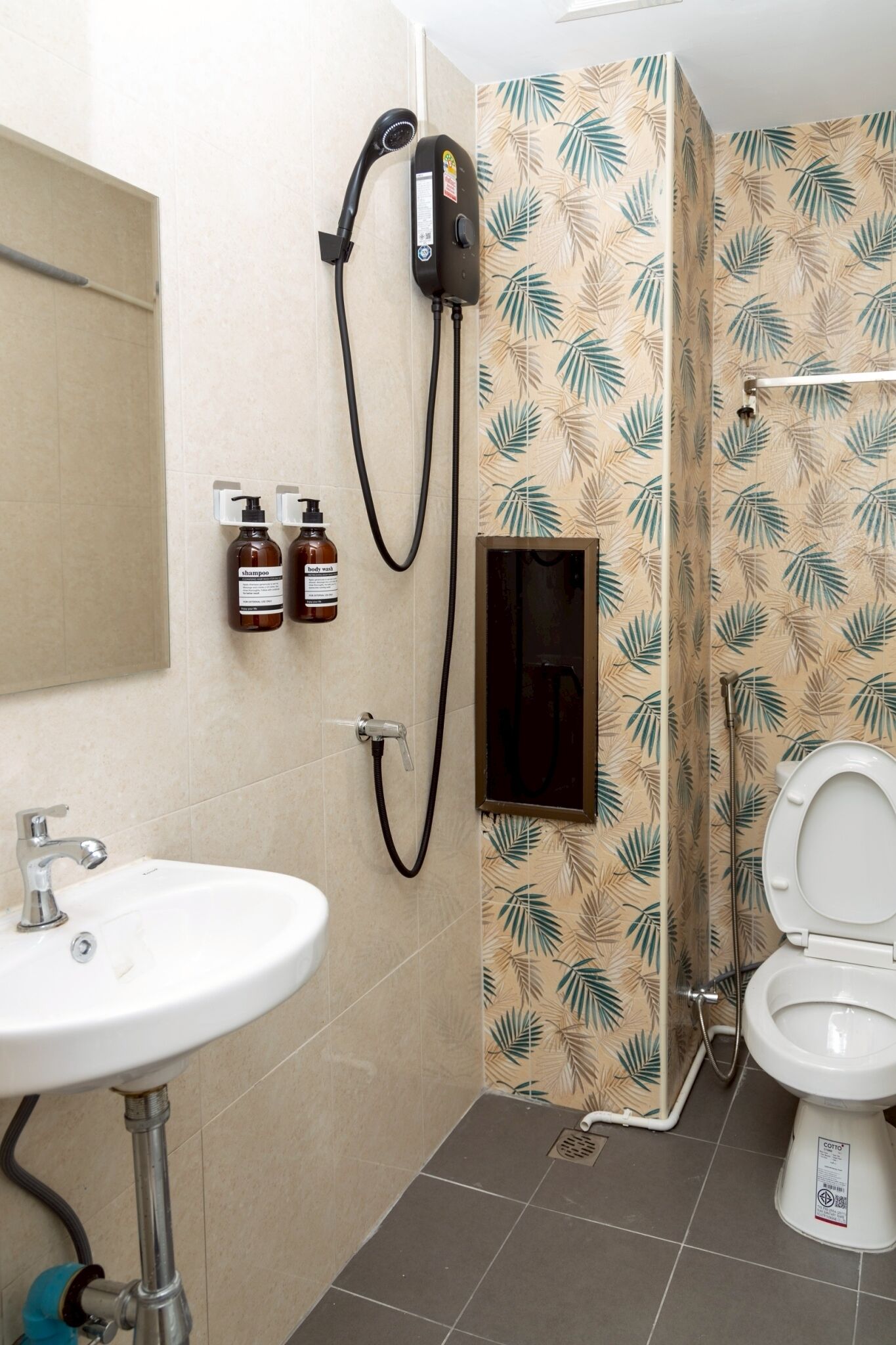 Un baño con ducha, inodoro, lavamanos y dos botellas de champú.