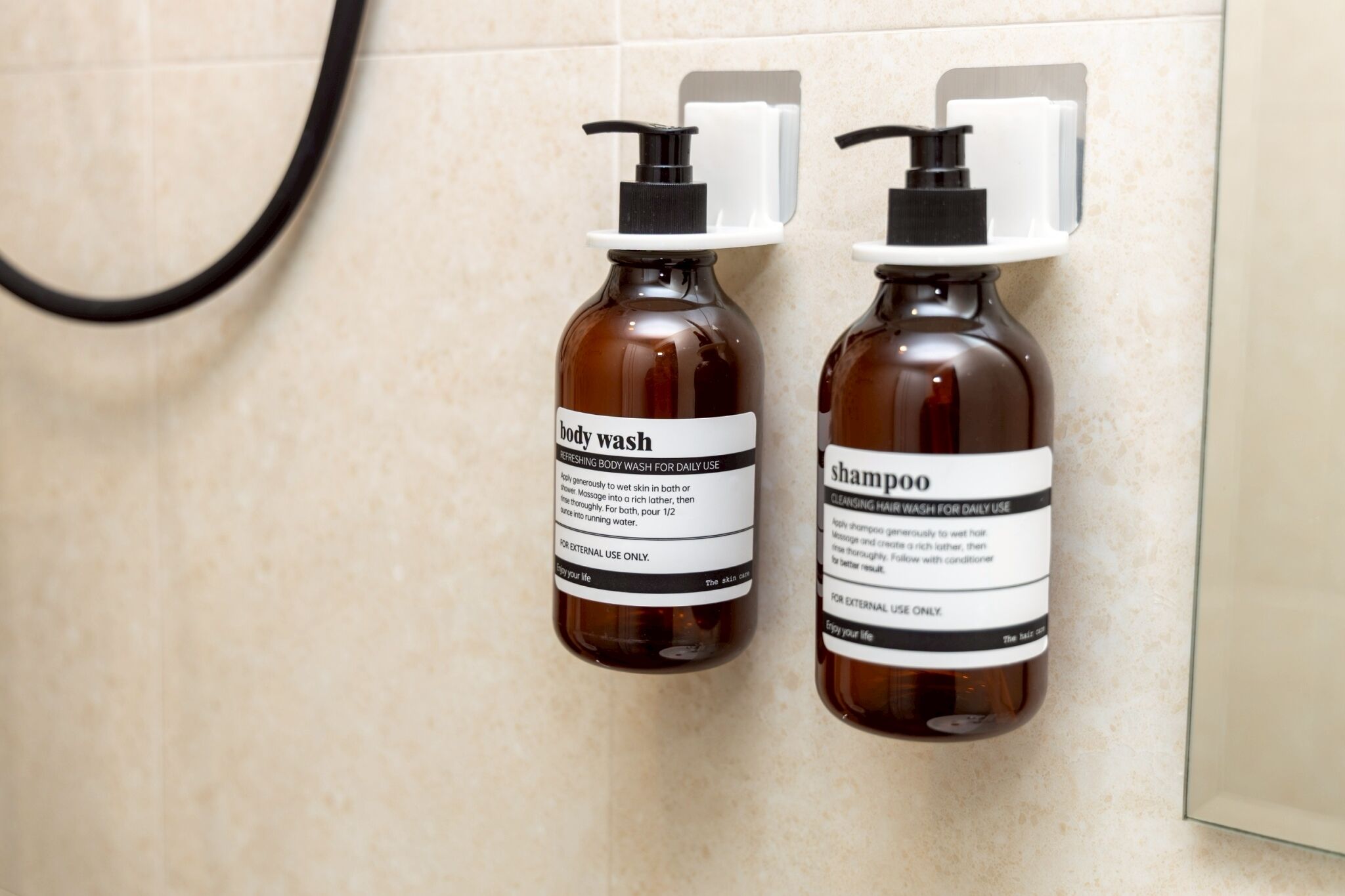Twee bruine flessen douchegel en shampoo hangen aan een muur.