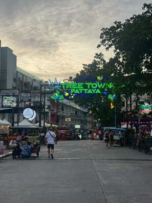 A street scene with a neon sign reading "TREE TOWN PATTAYA" and various shops and stalls. - Sea Inn Pattaya (Pattaya)