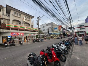 A street with parked motorcycles, a 7-Eleven store, and various shops. - Sea Inn Pattaya (Pattaya)