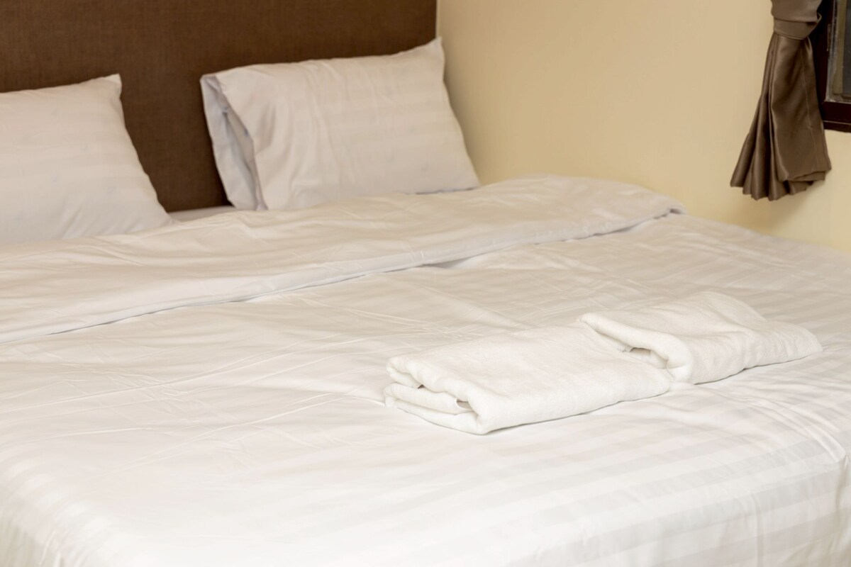 A neatly made bed with white linens and a folded towel.