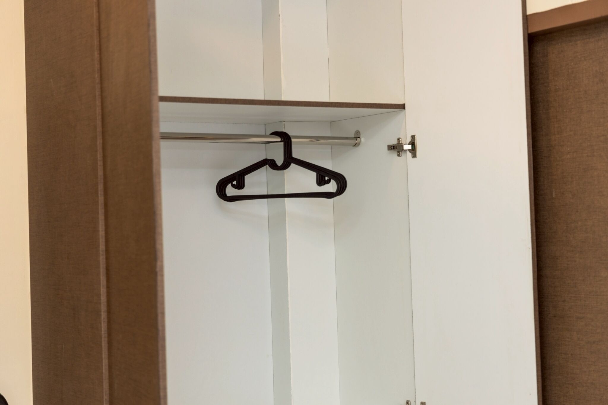 A white closet with a black hanger on a rod.