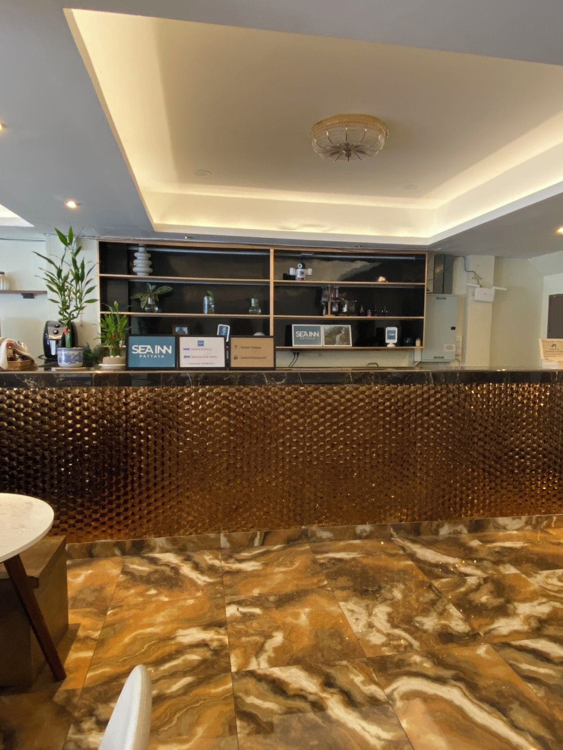 A reception area with a marble floor, a reception desk with a decorative wall, and a ceiling light fixture.