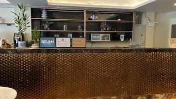 A reception area with a marble floor, a reception desk with a decorative wall, and a ceiling light fixture.