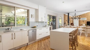 A modern kitchen with white cabinetry, a central island, and large windows.