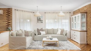A living room with a beige sofa, a white coffee table, and a cabinet with glass doors.