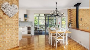 A modern kitchen with white cabinets, a wooden dining table, and a chandelier.