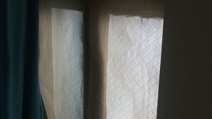 Ein Fenster mit einem Gittermuster, teilweise von einem Vorhang verdeckt.