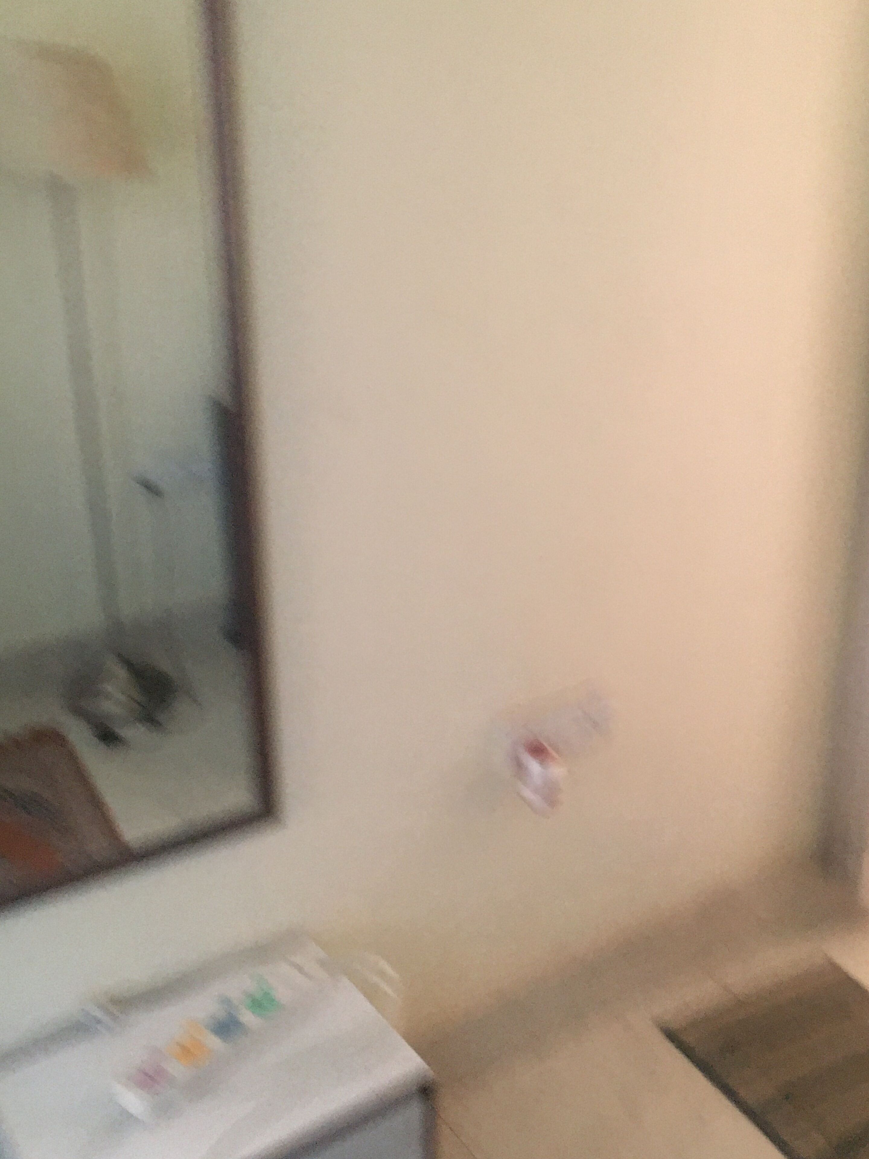 A room with a bed, a bedside table, and a wall-mounted mirror.