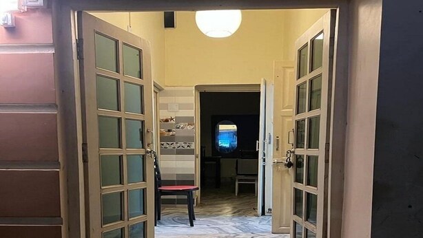 Ein Flur mit Glastüren zu einem Raum, der eine geflieste Spritzschutzwand und einen kleinen, runden Spiegel hat.