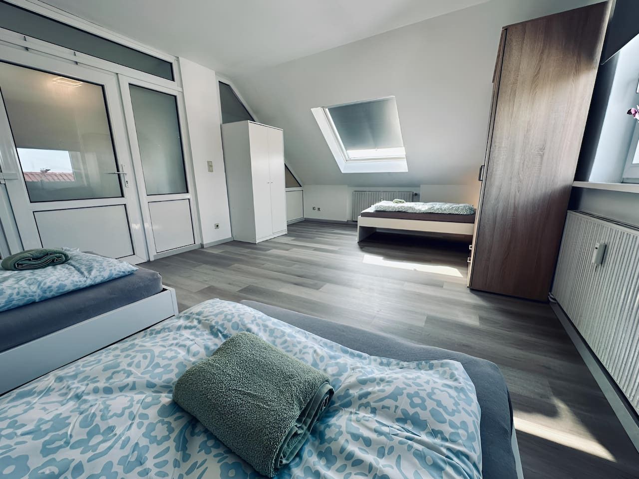Een moderne loft slaapkamer met dakraam, inbouwkast en een gezellige zithoek.