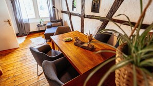 Un comedor con una mesa de madera, sillas grises y una planta al frente.