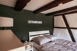 A bedroom with a bed, a nightstand, a lamp, and a wall with a sign.