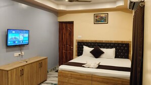 Quarto de hotel com cama, guarda-roupa de madeira, televisão e ventoinha no teto.