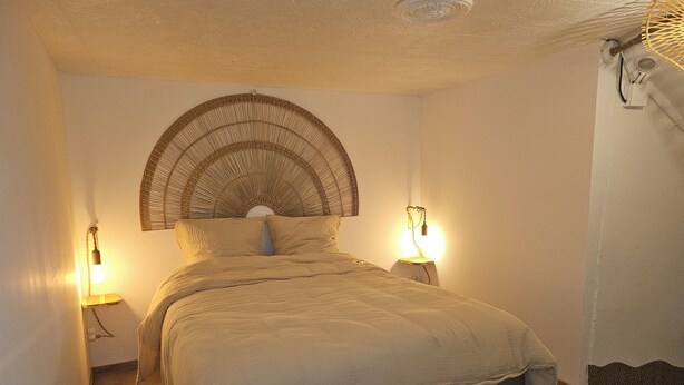 A bedroom with a bed, two bedside lamps, a wall-mounted light fixture, and a textured ceiling. - 54m² cocooning apartment in the center of St Cannat (Saint-Cannat)