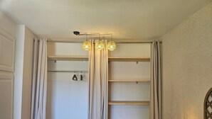 A bedroom with a walk-in closet, a bedside table with a lamp, and a bed. - 54m² cocooning apartment in the center of St Cannat (Saint-Cannat)