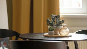 Une petite table ronde sur laquelle sont posés un cactus en pot et une bouteille en verre, le tout sur un dessous de verre.