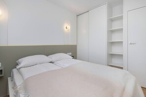 Une chambre à coucher comprenant un lit, une table de chevet, une lampe fixée au mur et une armoire.