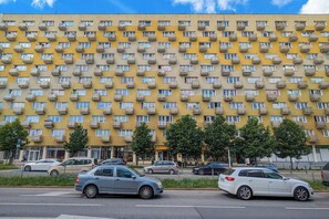 Un immeuble résidentiel à plusieurs étages, doté de nombreux balcons et d’un espace de stationnement à l’avant.