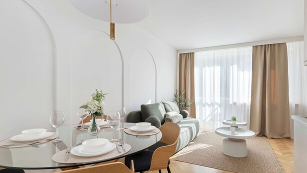 Un comedor moderno con una mesa de vidrio, sillas y un sofá al fondo.