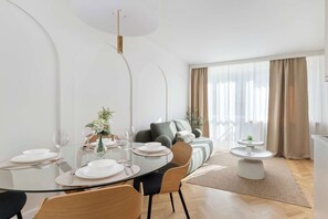 Un espace de repas moderne avec une table en verre, des chaises et un canapé en arrière-plan.
