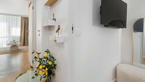 Una sala de estar moderna con una televisión de pantalla plana montada en la pared, una mesa redonda de cristal con una planta y un sofá.