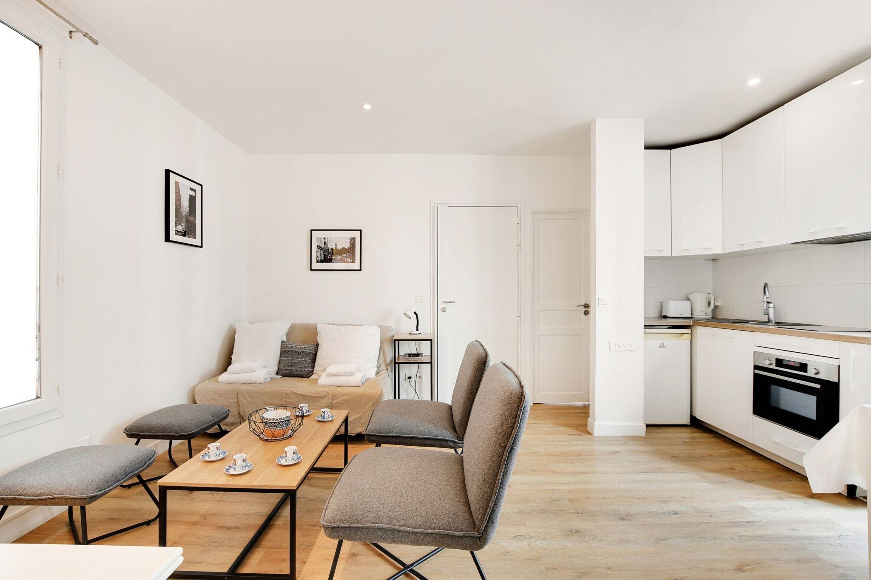 A modern living room with a sofa, a dining table, and a kitchen area.