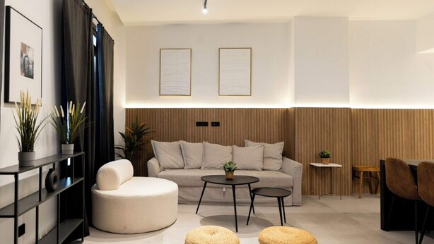 A modern living room with a sofa, round ottomans, a coffee table, and a side table with a plant. - Luxury Apt! 4BD/4BTH en suite (Madrid)