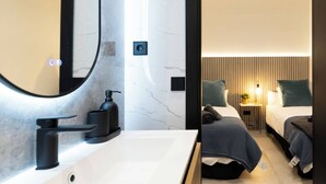 A modern bathroom with a large mirror, black faucet, and a marble wall. - Luxury Apt! 4BD/4BTH en suite (Madrid)