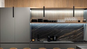 A modern kitchen with a marble backsplash, a built-in oven, and a dining area with a long table and chairs. - Luxury Apt! 4BD/4BTH en suite (Madrid)