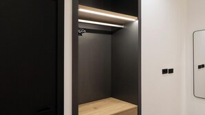 A modern, compact room with a built-in bench, a black door, and a wall-mounted light fixture. - Luxury Apt! 4BD/4BTH en suite (Madrid)