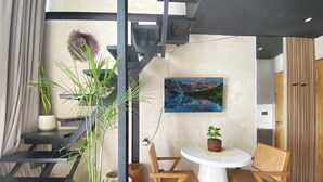 A modern room with a staircase, a dining table with chairs, a potted plant, and a painting on the wall. - Luxury Private Pool Loft Villa (Canggu)