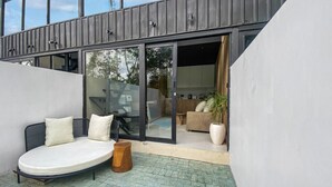 A modern outdoor seating area with a sofa, cushions, and a wooden stool. - Luxury Private Pool Loft Villa (Canggu)