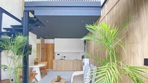 A modern interior with a kitchen, dining area, and seating space, featuring wooden elements and potted plants. - Luxury Private Pool Loft Villa (Canggu)