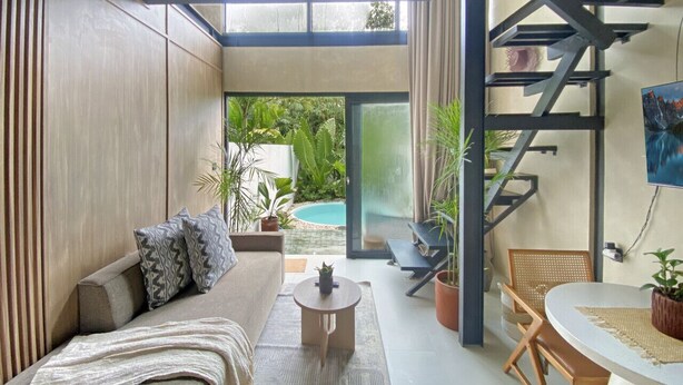 A modern living room with a sofa, coffee table, and chairs, a staircase, and a pool view. - Luxury Private Pool Loft Villa (Canggu)