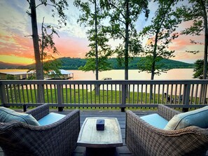 A deck with wicker furniture and a table, overlooking a lake and hills. - Lakefront w/ Private Dock + Sunset Views | Sleeps 8 | Near Boat Launch (Grant)