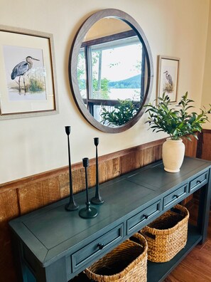 A dark wooden console table with framed bird paintings, a round mirror, and a potted plant. - Lakefront w/ Private Dock + Sunset Views | Sleeps 8 | Near Boat Launch (Grant)