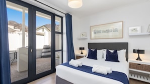 A hotel room with a large bed, a view of the mountains, and a balcony with outdoor furniture. - Uptown Retreat (Cape Town)