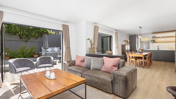 A modern living room with a sofa, a wooden coffee table, and a dining area with a table and chairs. - Uptown Retreat (Cape Town)