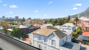 A residential area with various buildings, including a prominent white house with a red roof and a balcony. - Langholm 45 on Kloof (Cape Town)