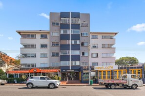 Un edificio de varios pisos con una entrada central, flanqueada por negocios a ambos lados.