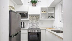 A compact kitchen with a stainless steel refrigerator, a microwave, an oven, and a sink. - Langholm 45 on Kloof (Cape Town)