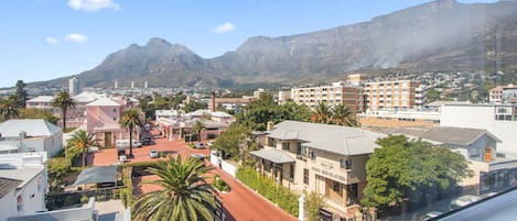 Un paisaje urbano con edificios, una calle y una montaña al fondo.